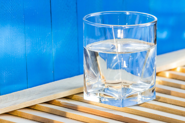 water in glas, op blauwe achtergrond - Foto, afbeelding