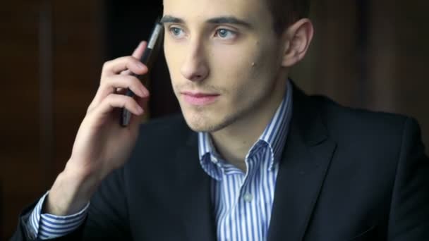 Zelfverzekerde knappe jonge man spreken op de telefoon in café - Video