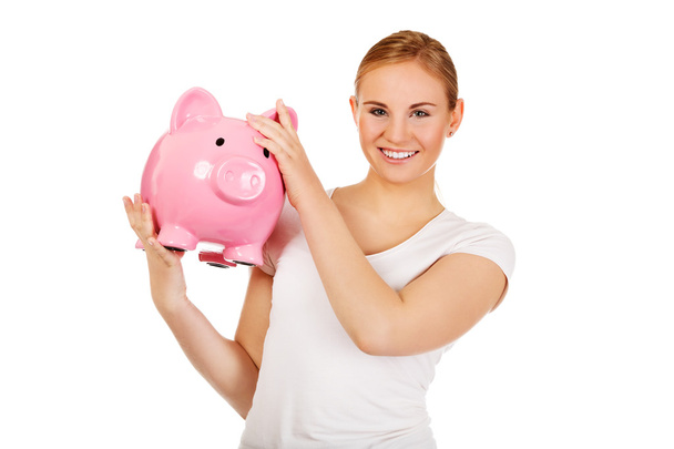 Happy young woman holding piggybank - Zdjęcie, obraz