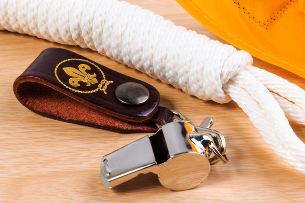 Metal whistle, yellow scout scarf and scout rope on wooden background. - Zdjęcie, obraz