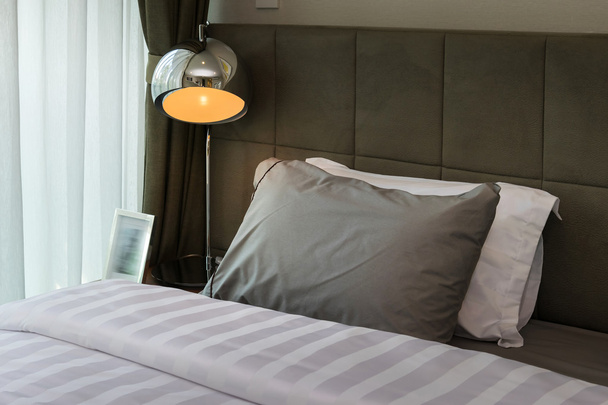 metal desk lamp and grey pillow on bed - Foto, Imagem