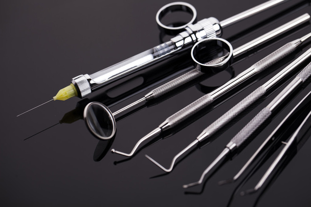 Крупный план профессиональных стоматологических инструментов на блестящем столе
 - Фото, изображение