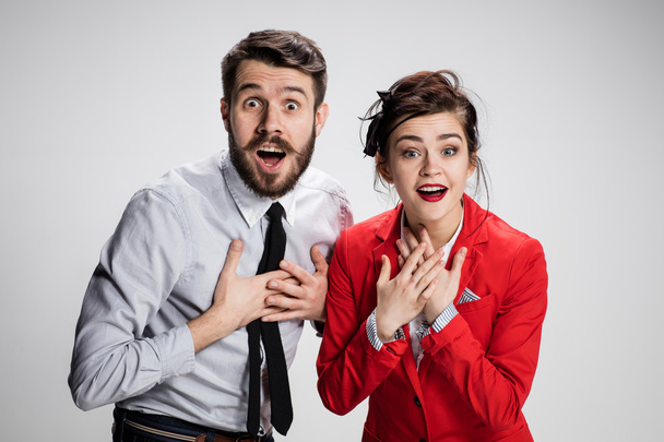 The surprised business man and woman smiling on a gray background - Fotó, kép