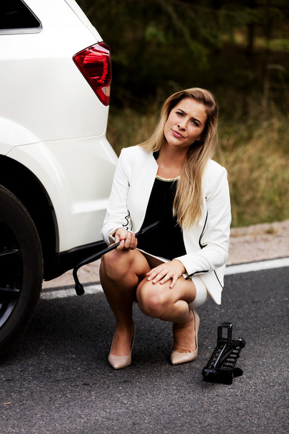 Young woman holding jacke and wheel wrench - Foto, Imagem