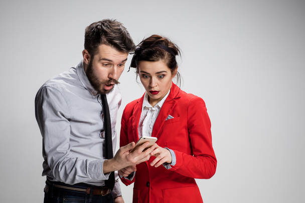 Business concept. The two young colleagues holding mobile phone on gray background - Fotografie, Obrázek