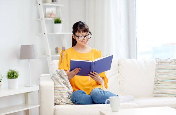 smiling young asian woman reading book at home - Фото, изображение