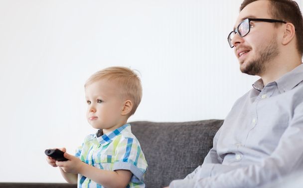 father and son with remote watching tv at home - Фото, зображення