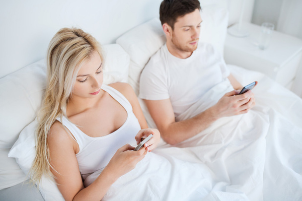 couple with smartphones in bed - Φωτογραφία, εικόνα