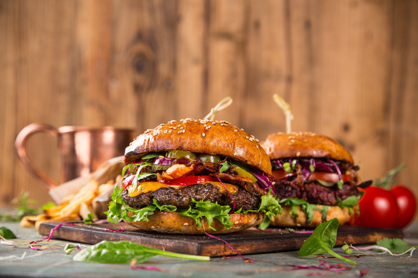 Tasty burgers on wooden table. - Фото, зображення