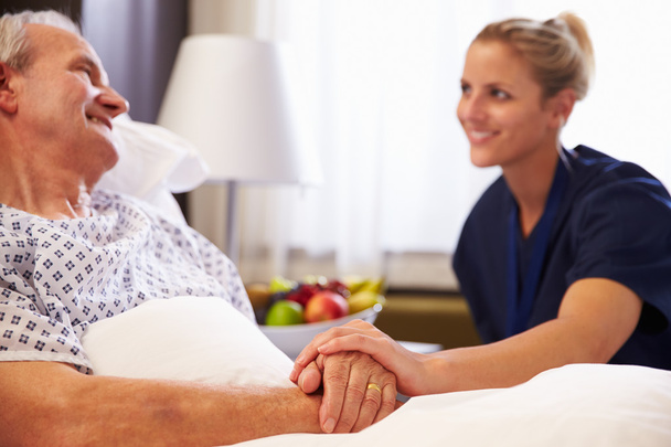 Nurse Talking To Senior Patient In Bed - 写真・画像