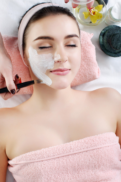 Woman with clay facial mask in beauty spa. - Photo, Image