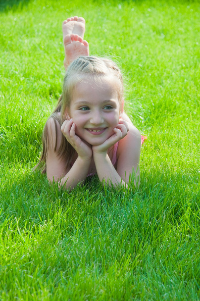 Happy little girl lying at the park - Фото, изображение