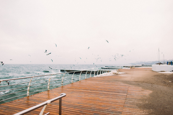 Long pier with seagulls  in the middle of a quiet bay on island - Фото, изображение