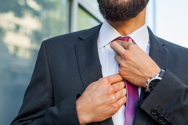 Young attractive businessman ajusting his tie. Outdoor photo. - Fotoğraf, Görsel