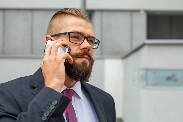 Young bearded businessman wearing eyeglasses using mobile phone  - Foto, Bild
