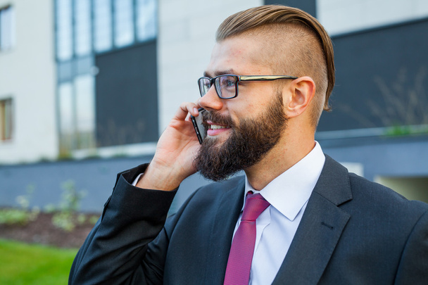 Young bearded businessman wearing eyeglasses using mobile phone  - Zdjęcie, obraz