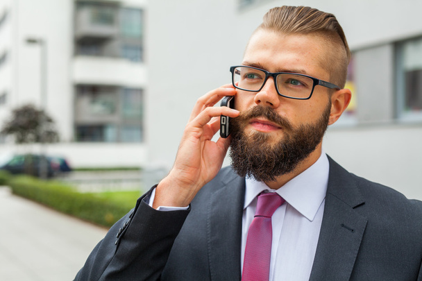 Young bearded businessman wearing eyeglasses using mobile phone  - 写真・画像