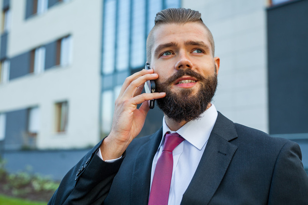 Young bearded businessman wearing eyeglasses using mobile phone  - Foto, immagini