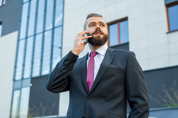 Young bearded businessman wearing eyeglasses using mobile phone  - Фото, изображение