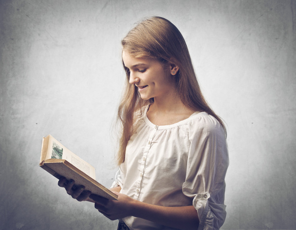 Улыбающаяся девочка-подросток, читающая книгу
 - Фото, изображение