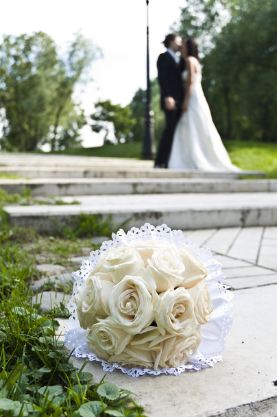bruiloft boeket met het huwelijkspaar op de achtergrond - Foto, afbeelding