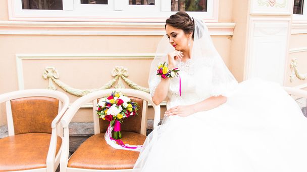 Красивая невеста со свадебным букетом цветов на открытом воздухе в парке
. - Фото, изображение