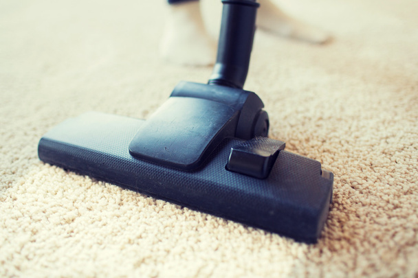 close up of vacuum cleaner cleaning carpet at home - Foto, afbeelding