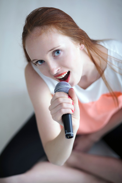 Червона голова молода жінка тримає з мікрофоном і сидить
 - Фото, зображення
