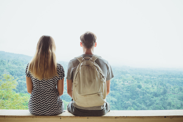 Back view of a young man and woman enjoying amazing view while s - 写真・画像