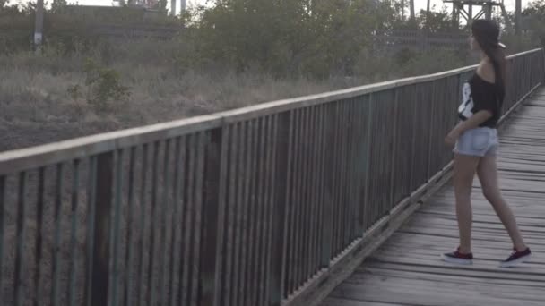 Wit meisje in korte broek lopen op de houten brug - Video