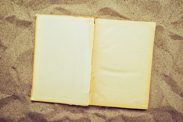 Open vintage book in warm beach sand - Fotó, kép