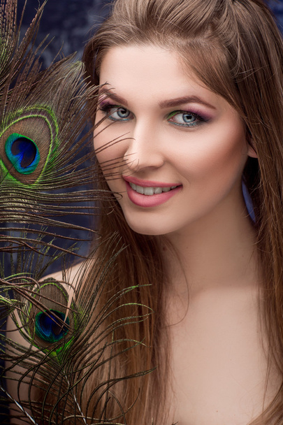 girl with bright  makeup and peacock feathe - Фото, изображение