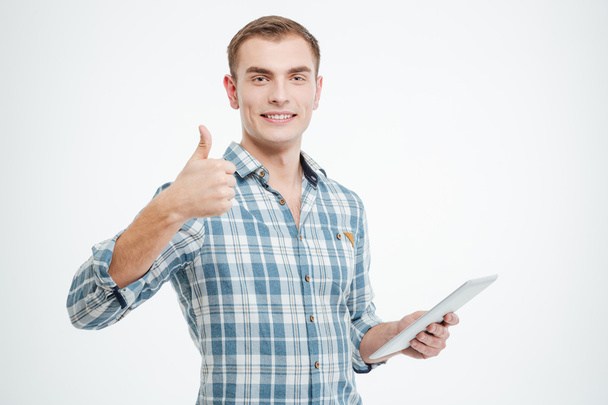 Smiling handsome young man using tablet and showing thumbs up  - Photo, image