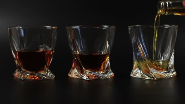 Whiskey, egy üveg fekete háttér ellenében öntik - Felvétel, videó