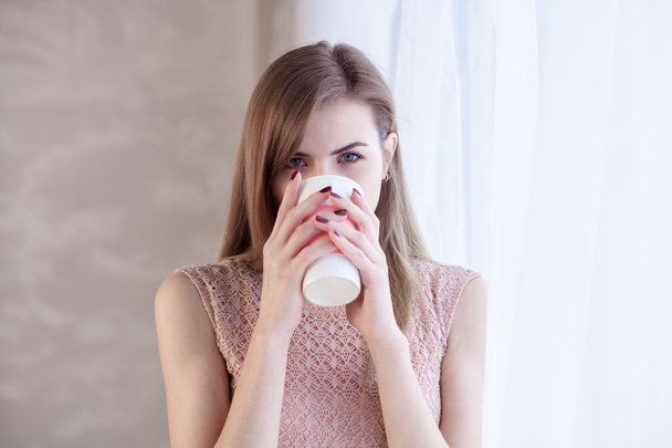 the girl at the window, drinks from a mug - Photo, image