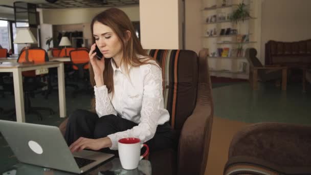 Frau arbeitet mit Laptop und telefoniert - Filmmaterial, Video