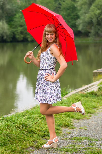 Jeune femme avec parapluie rouge près de l'étang
 - Photo, image