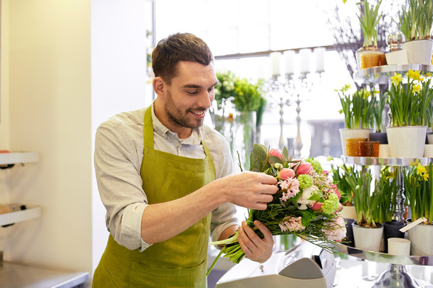 smiling florist man making bunch at flower shop - Фото, изображение