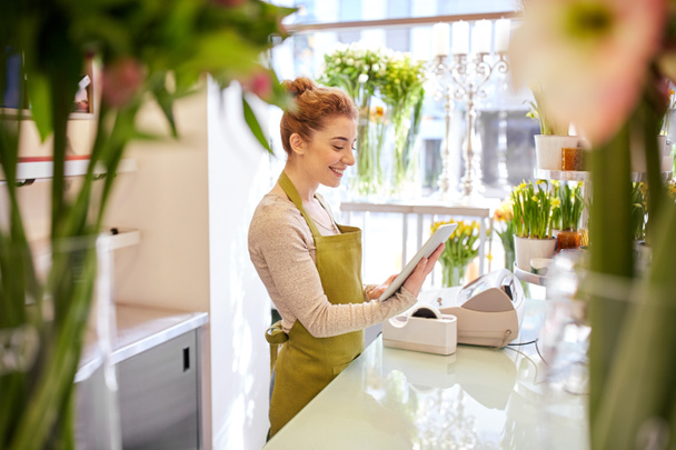 woman with tablet pc computer at flower shop - Foto, Bild