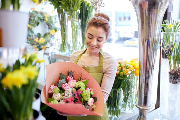 smiling florist woman with bunch at flower shop - Zdjęcie, obraz