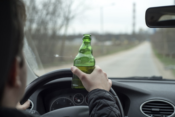 νεαρός άνδρας οδήγηση του αυτοκινήτου, ενώ το πόσιμο αλκοόλ - Φωτογραφία, εικόνα