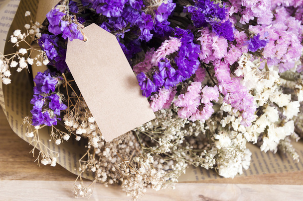 Boeket gedroogde bloemen met blanco papier tag op de houten tabl - Foto, afbeelding