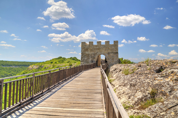 Каменные стены и ворота с деревянным мостом на средневековой крепости
 - Фото, изображение