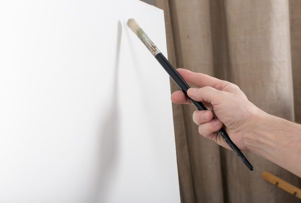 An artist painting on white canvas in studio - Фото, изображение