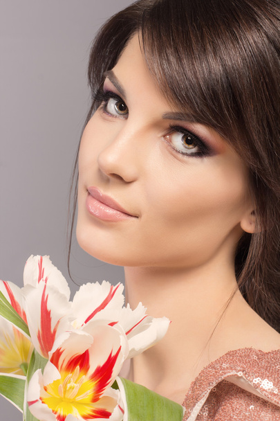 Beauty Girl with flovers. Beautiful Young Woman with Fresh Clean Skin, Beautiful Face. Pure Natural Beauty. Perfect Skin. Isolated on a Grey Background.  - Foto, imagen