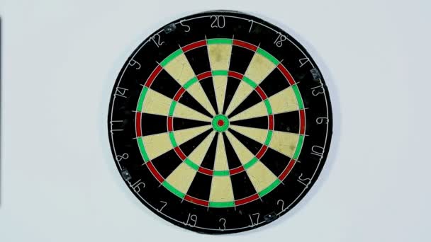 A dart strikes the bulls-eye of a dartboard. Wide shot of a dart board from below, three darts with a bull's eye.  - Footage, Video