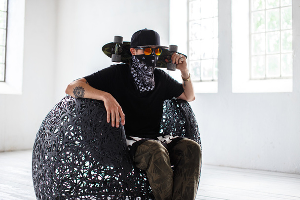 man in masker houdt skateboard - Foto, afbeelding