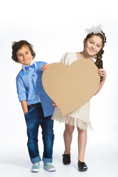 Boy and girl holding a cardboard heart. Love concept - Foto, imagen