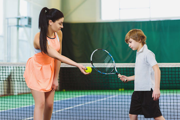 Young woman or coach teaching child how to play tennis on a court indoor - Foto, Imagem