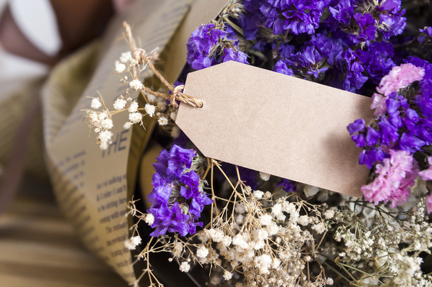 Букет сушеных цветов с чистым бумажным биркой на деревянном столе
 - Фото, изображение